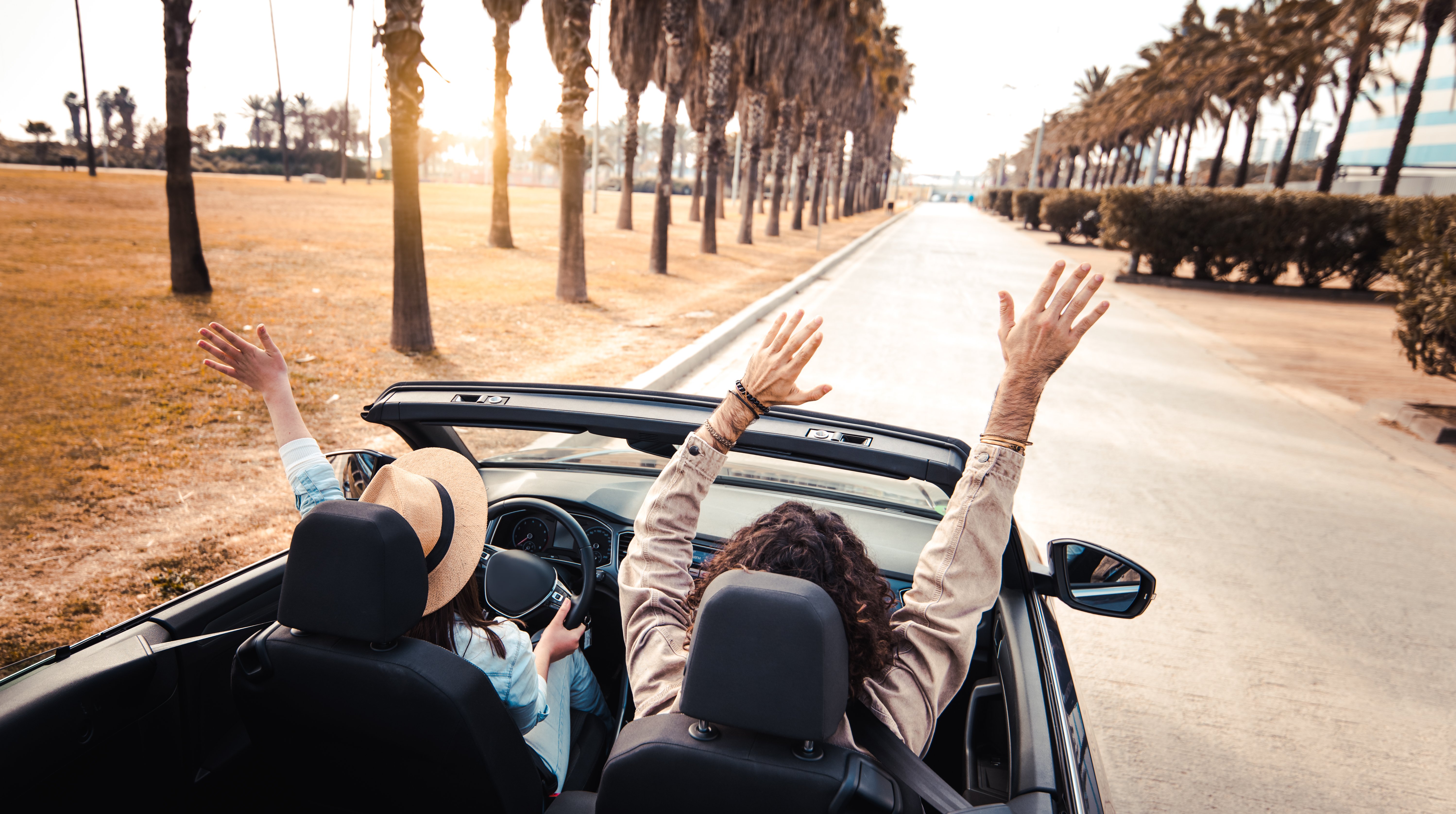 happy-couple-driving-on-city-street-in-convertible-2023-11-27-05-04-43-utc